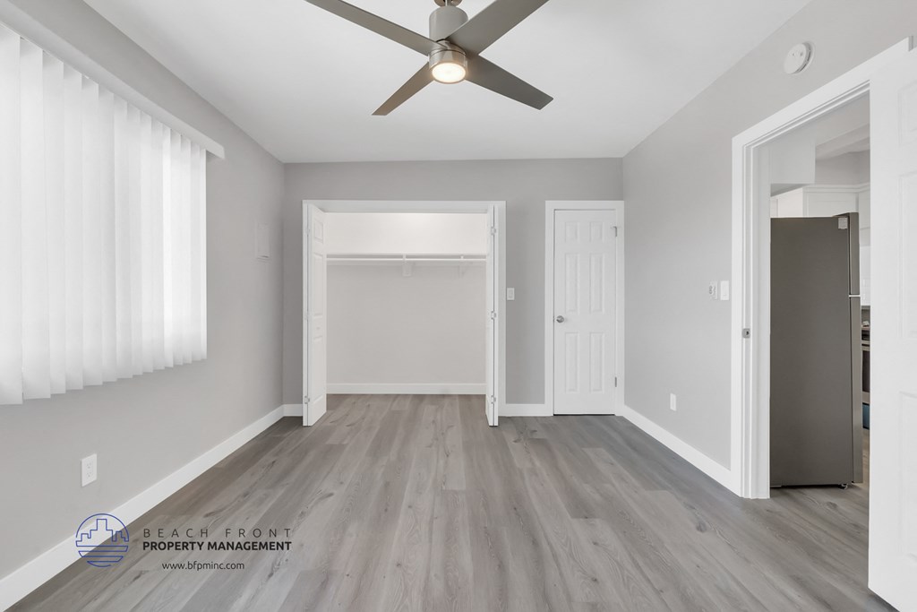 the living room of a new home with white walls and a ceiling fan