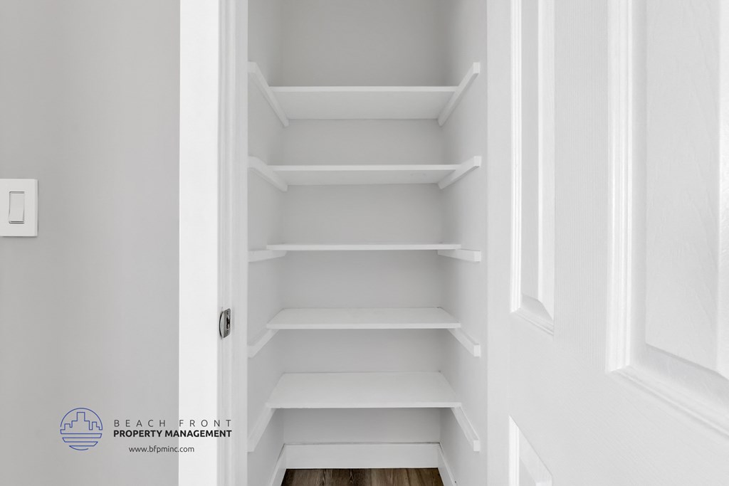 a small closet with white shelves and white walls