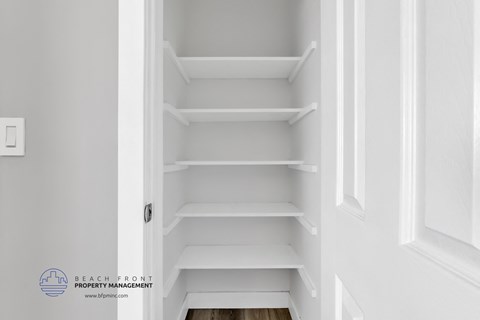 a small closet with white shelves and white walls
