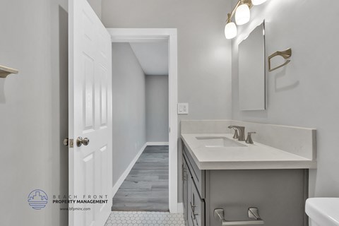 a bathroom with a sink and a mirror and a hallway to a toilet and shower