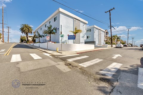 a white building with palm trees on the corner of a street