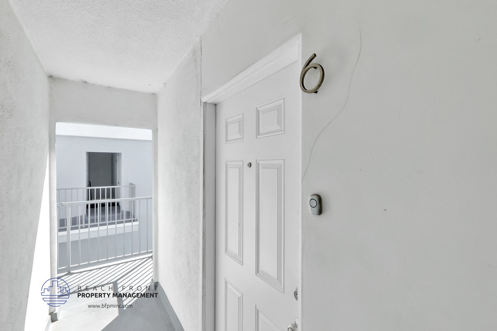 a white door with a door knob and a balcony in a white apartment building