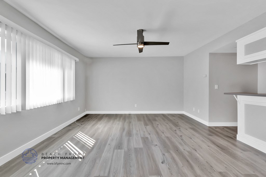 an empty living room with hardwood floors and a ceiling fan
