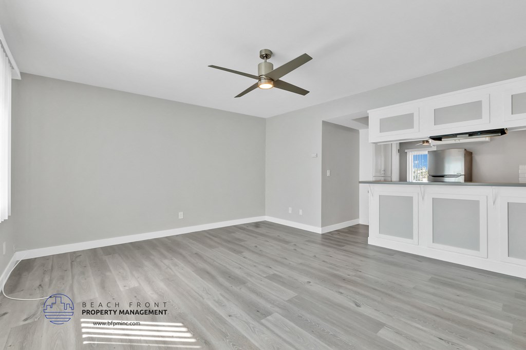a living room with a ceiling fan and a kitchen
