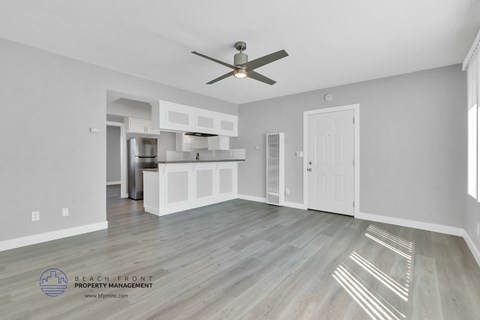 a living room with a ceiling fan and a kitchen