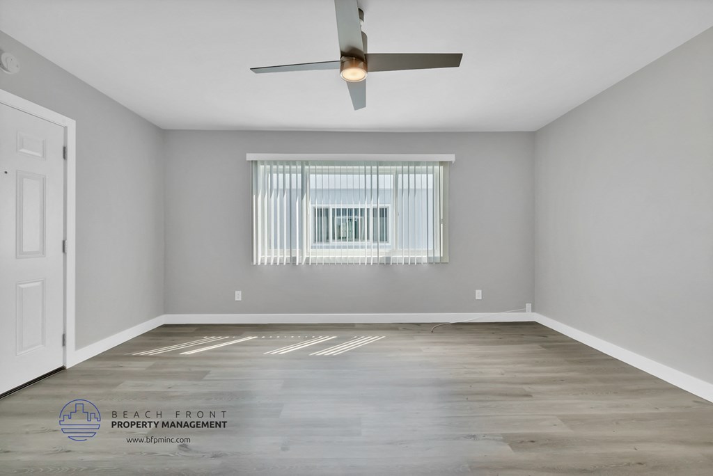 the living room of a rental house with a window and a ceiling fan