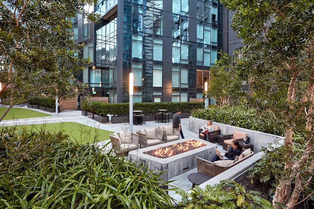 a courtyard with a fire pit and furniture in front of an office building
