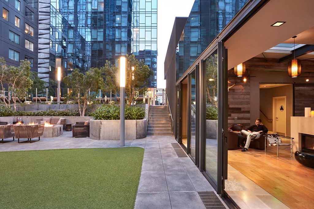 a terrace with grass and chairs and tall buildings