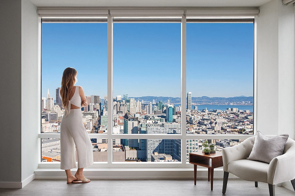 a woman standing in front of a window looking out at a city skyline