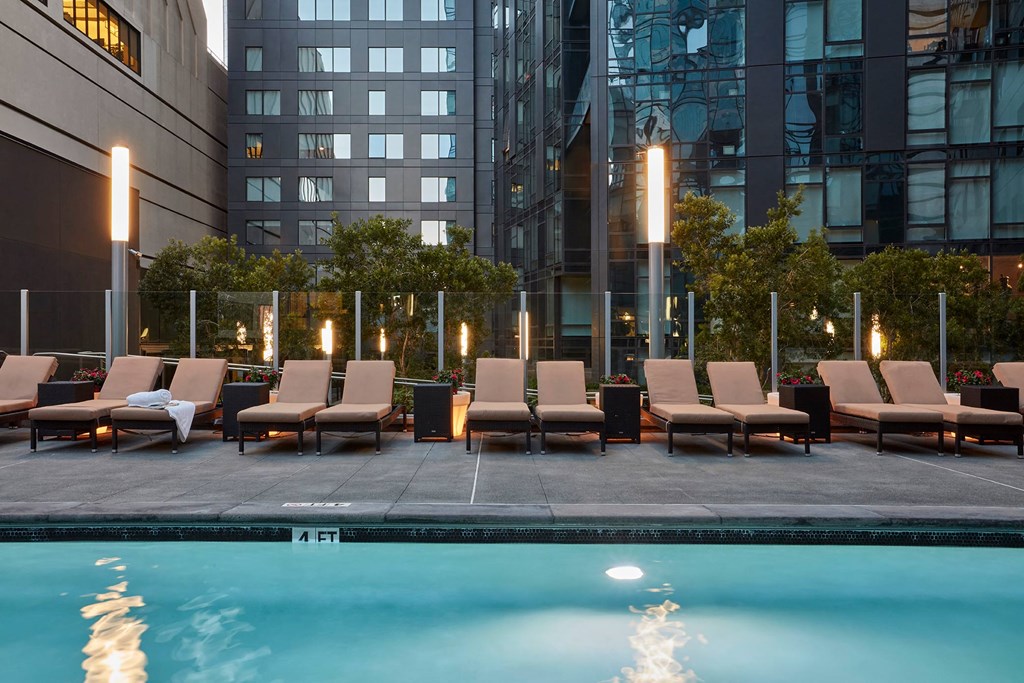 a pool with lounge chairs next to a hotel pool