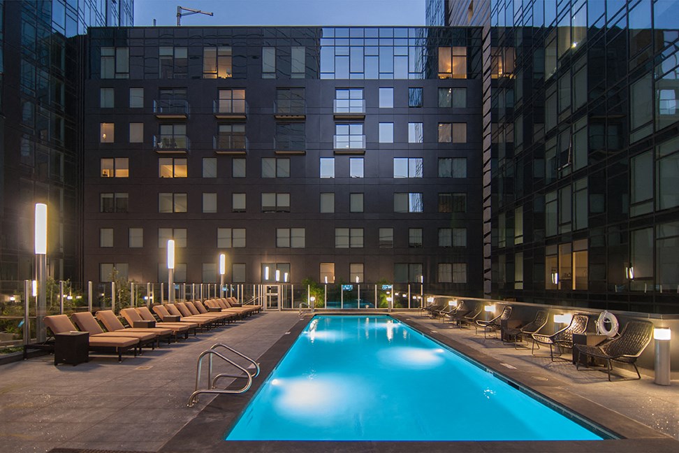 a swimming pool at night in front of a tall building