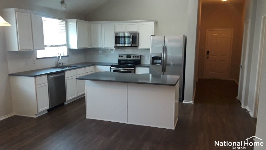 A kitchen with white cabinets and a black countertop.