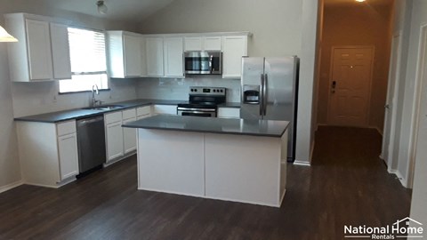 A kitchen with white cabinets and a black countertop.