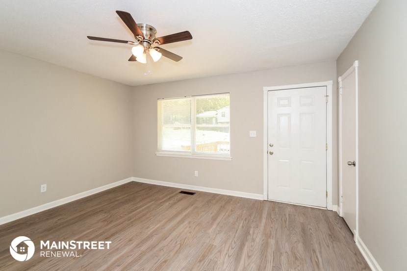the living room of this home has a large window and a ceiling fan