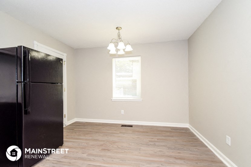 the interior of an empty room with a refrigerator and a window