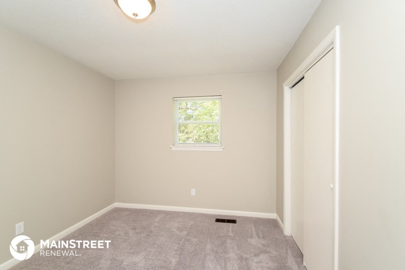 the upstairs bedroom with carpeted flooring and a window