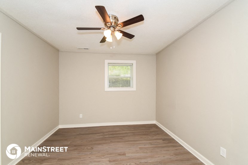 the spacious living room with ceiling fan and wood flooring