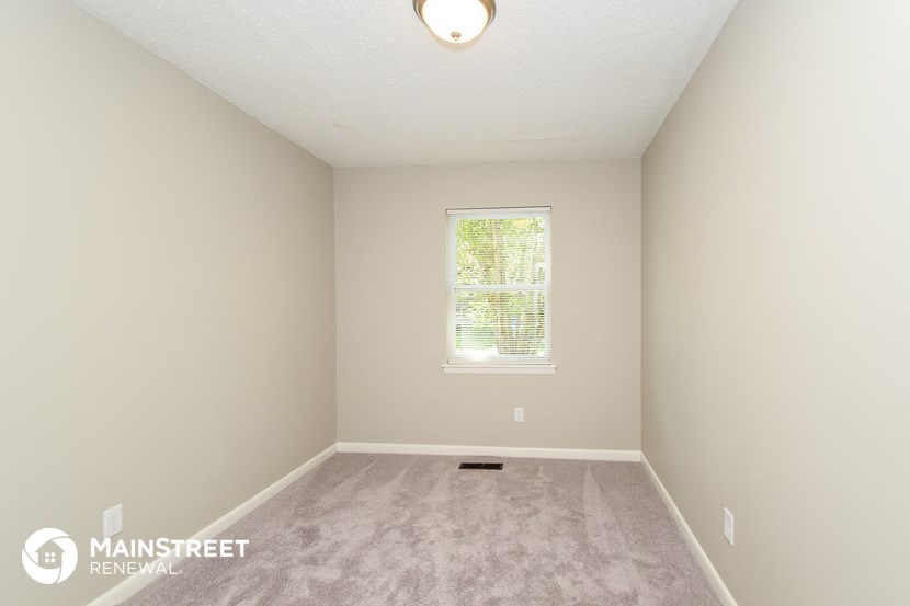 the upstairs bedroom with carpeted flooring and a window