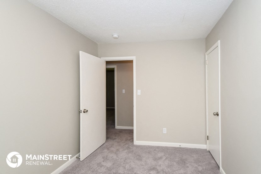 a bedroom with a carpeted floor and a door to a closet