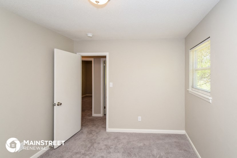 a bedroom with a carpeted floor and a door to a closet