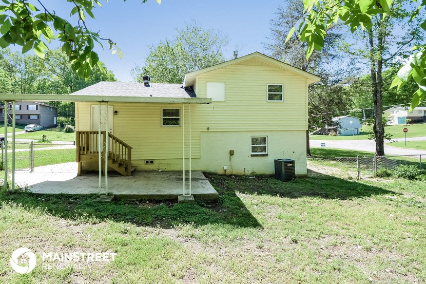 a small yellow house with a porch and a tree