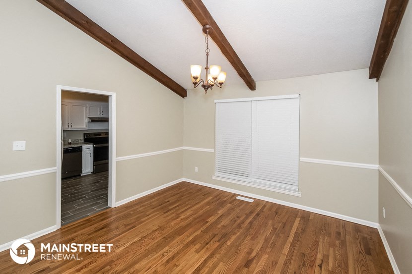 the living room of a home with a wood floor and a window with a blind