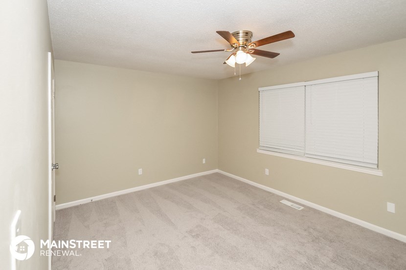 an empty living room with a ceiling fan and a window