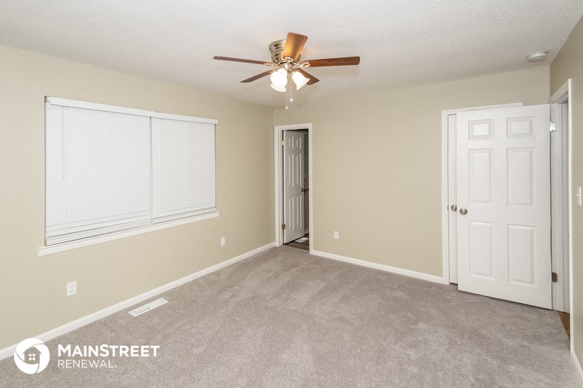 the living room of an empty house with a ceiling fan