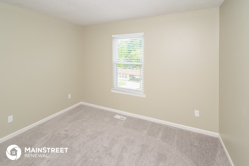 an empty room with a window and carpet