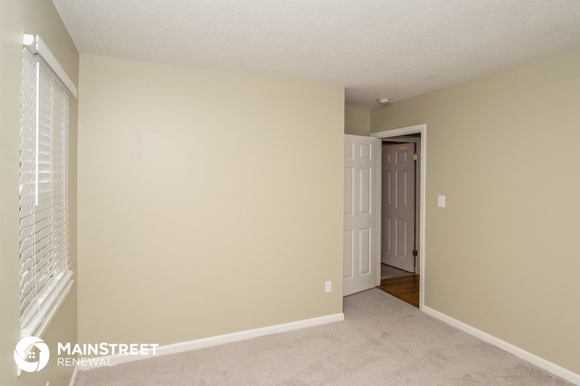 the living room of an apartment with a door to the hallway