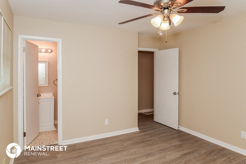 a bedroom with a ceiling fan and a door to a bathroom