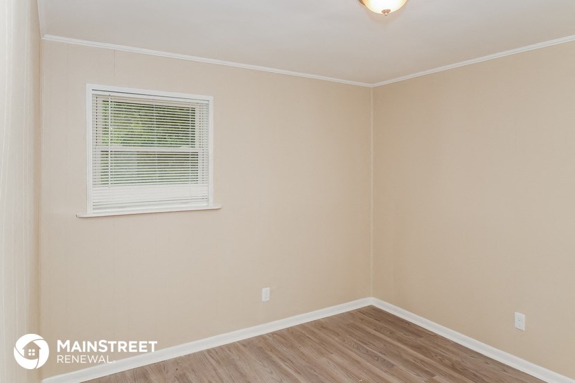 the upstairs bedroom of this 2500 sq ft home has a wood floor and a window