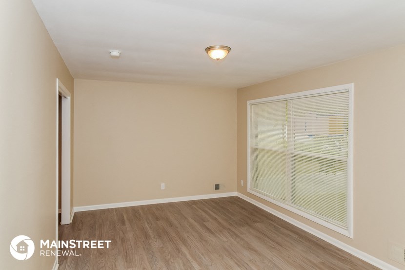 the spacious living room with large window and wood flooring