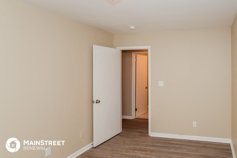 the bedroom of an apartment with a door open to the hallway