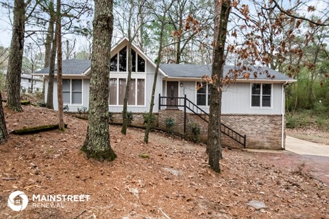 a small white house in the woods with trees