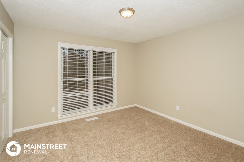 the spacious living room has a large window and carpeted flooring