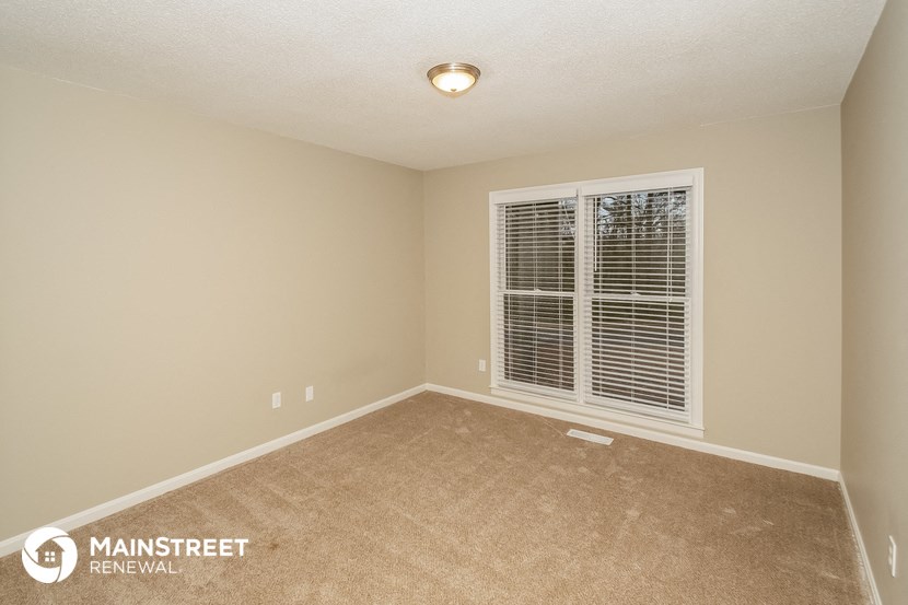 a bedroom with a large window and a carpeted floor