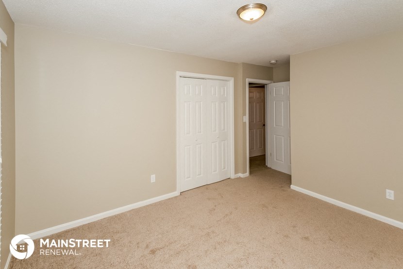 a spacious living room with a door to the hallway and a closet