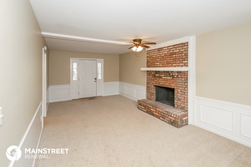 a living room with a brick fireplace and a ceiling fan