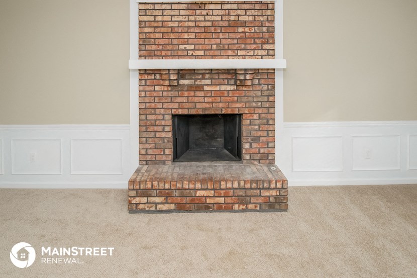 a brick fireplace in a living room with white walls and carpet