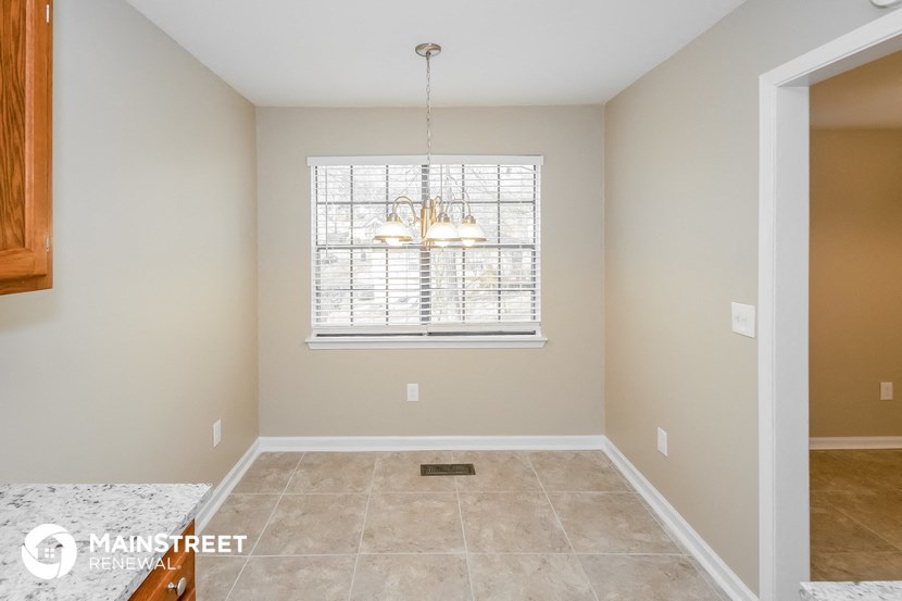 an empty dining room with a window and a chandelier