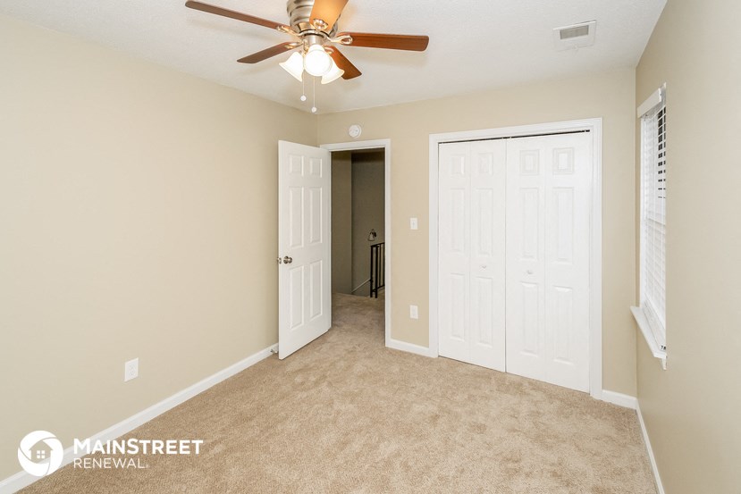 a bedroom with a ceiling fan and a door to a closet