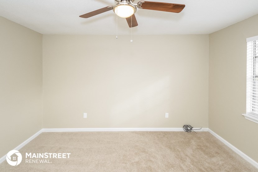an empty living room with a ceiling fan