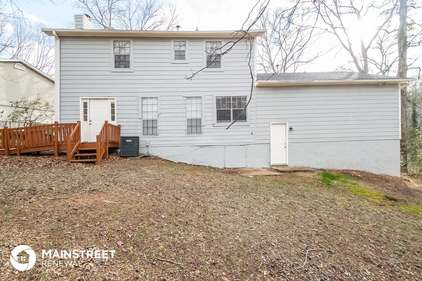 the back of a white house with a wooden deck