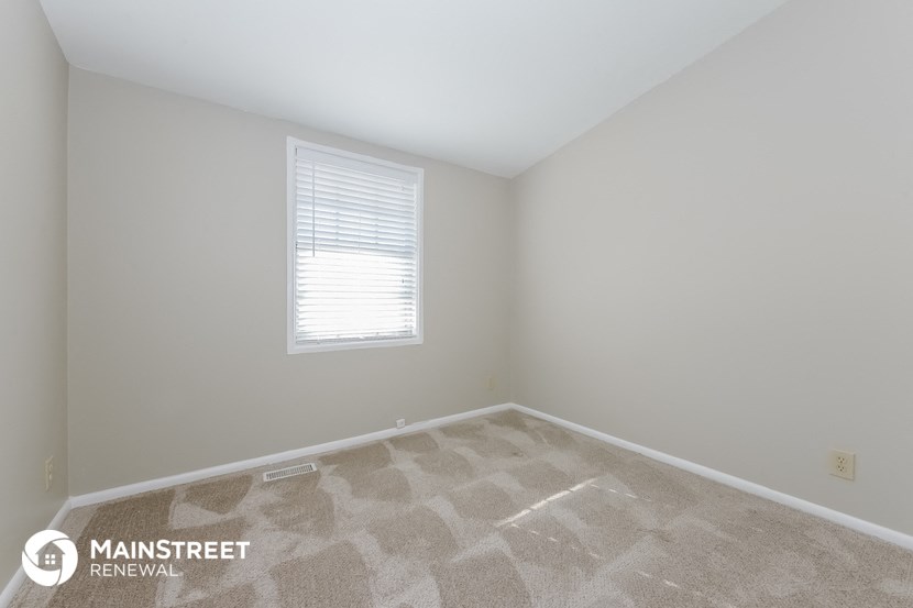 the bedroom of a home with a carpeted floor and a window