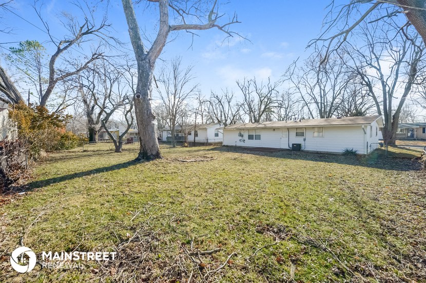 a small white house in a grassy yard with trees