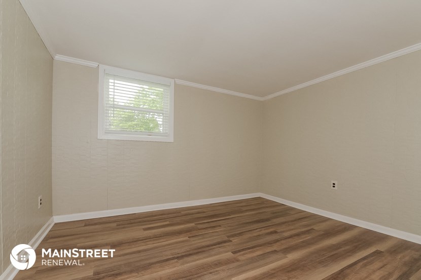 the living room of a home with wood floors and a window