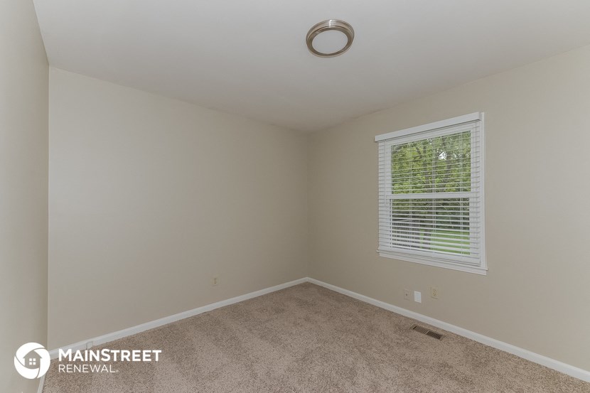 a bedroom with a large window and a carpeted floor