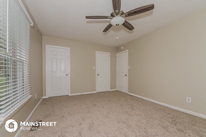 an empty living room with a ceiling fan and two doors