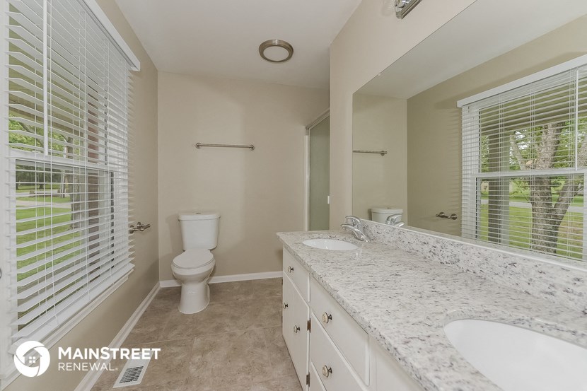 a bathroom with two sinks and a toilet and a mirror